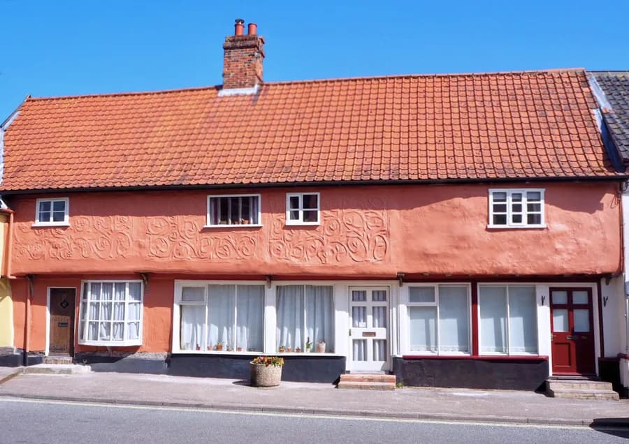 Ein Cottage von 1600 in Ixworth im traditionellen Suffolk-Rosa, dem Ton der Kalkanstriche der Grafschaft: die Farbe steckt in der Schicht, das Relief des Putzes bleibt darunter lesbar.